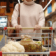 woman grocery shopping pushing cart with apples and cauliflower