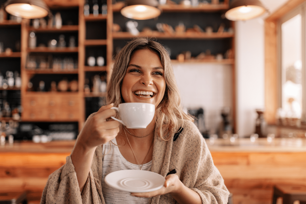 how to splurge on a budget woman drinking fancy coffee luxury treat smiling