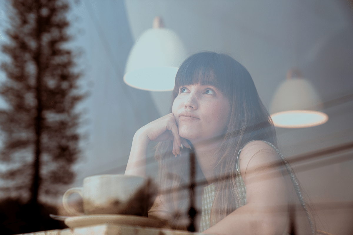 woman daydreaming coffee shop window.