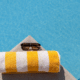 best inexpensive beach towel with sunglasses on edge of swimming poo