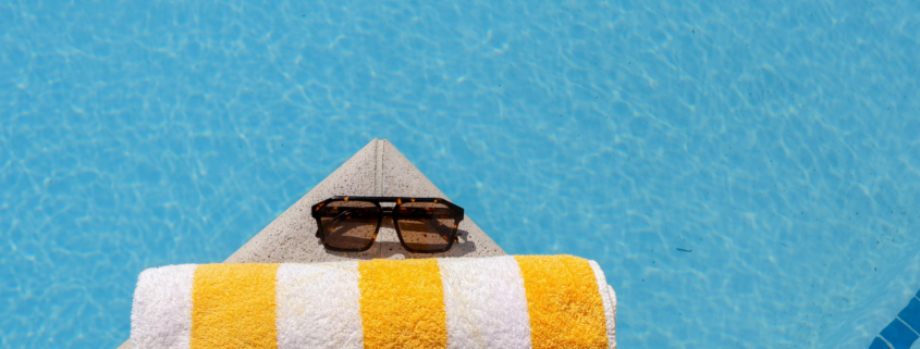 best inexpensive beach towel with sunglasses on edge of swimming poo