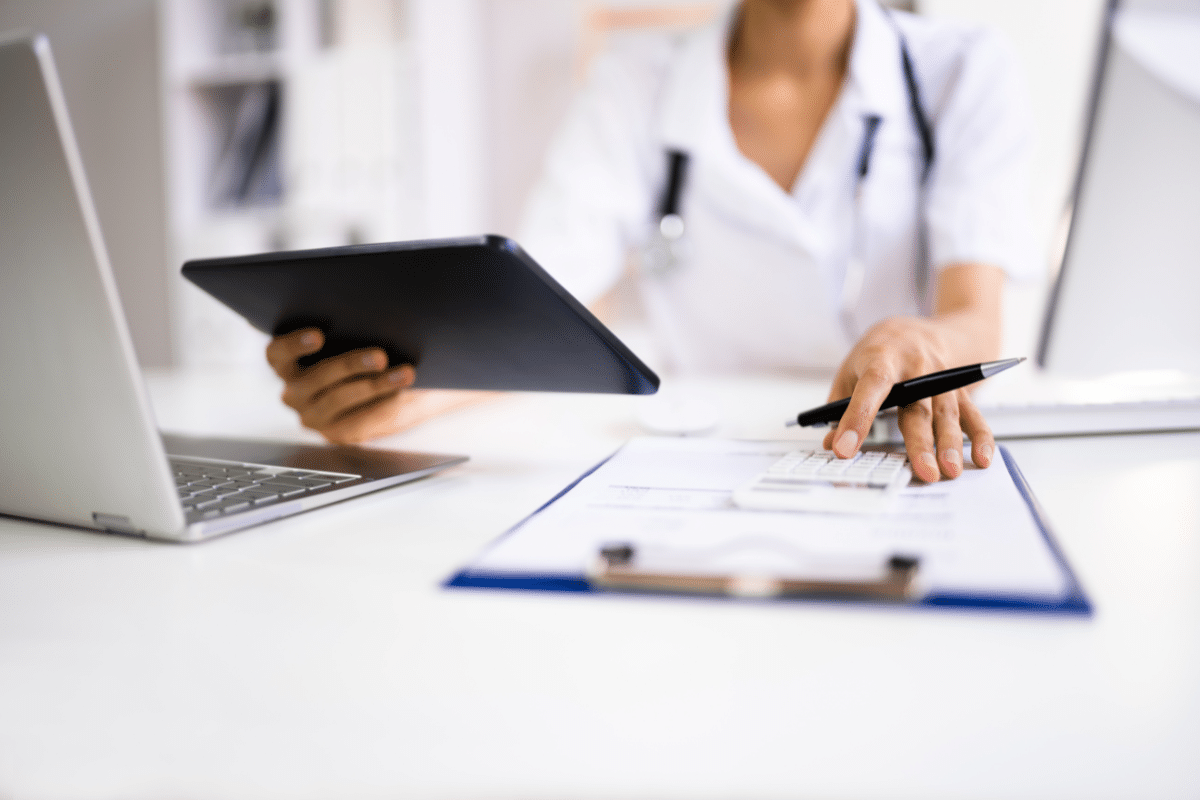 negotiate medical bills female nurse with calculator and ipad negotiating a bill