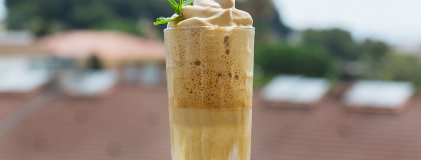 creamy whipped frozen coffee drink on balcony with whipped cream