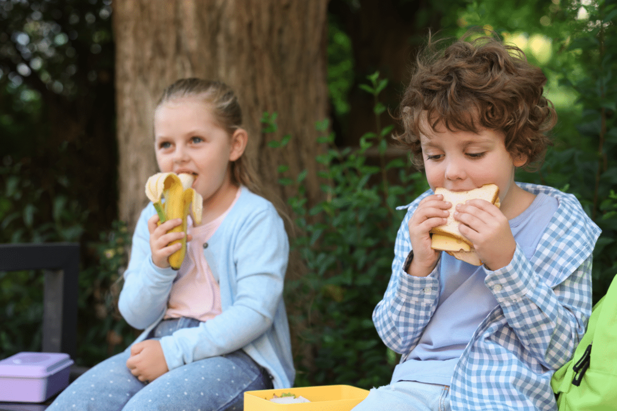 what to pack for kids lunchboxes young boy and girl eating a banana and a sandwich