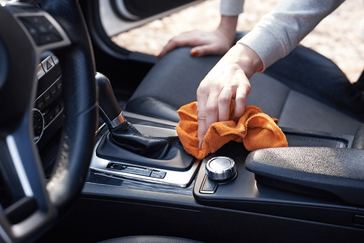 woman using a microfiber to wipe interior of car