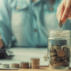 high yield savings account man dropping quarter into mason jar
