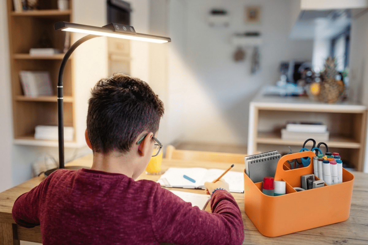 young boy with caddy school supplies and task lamp