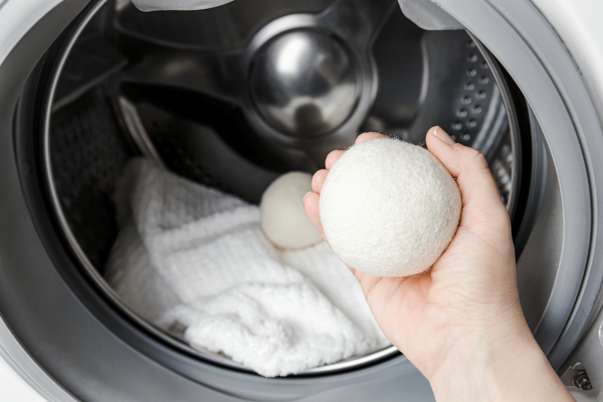 woman throwing wool dryer ball into laundry