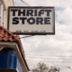 thrift store sign with blue cloudy sky in background