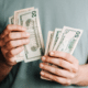 affluence more money isn't the answer man holding dollar bills