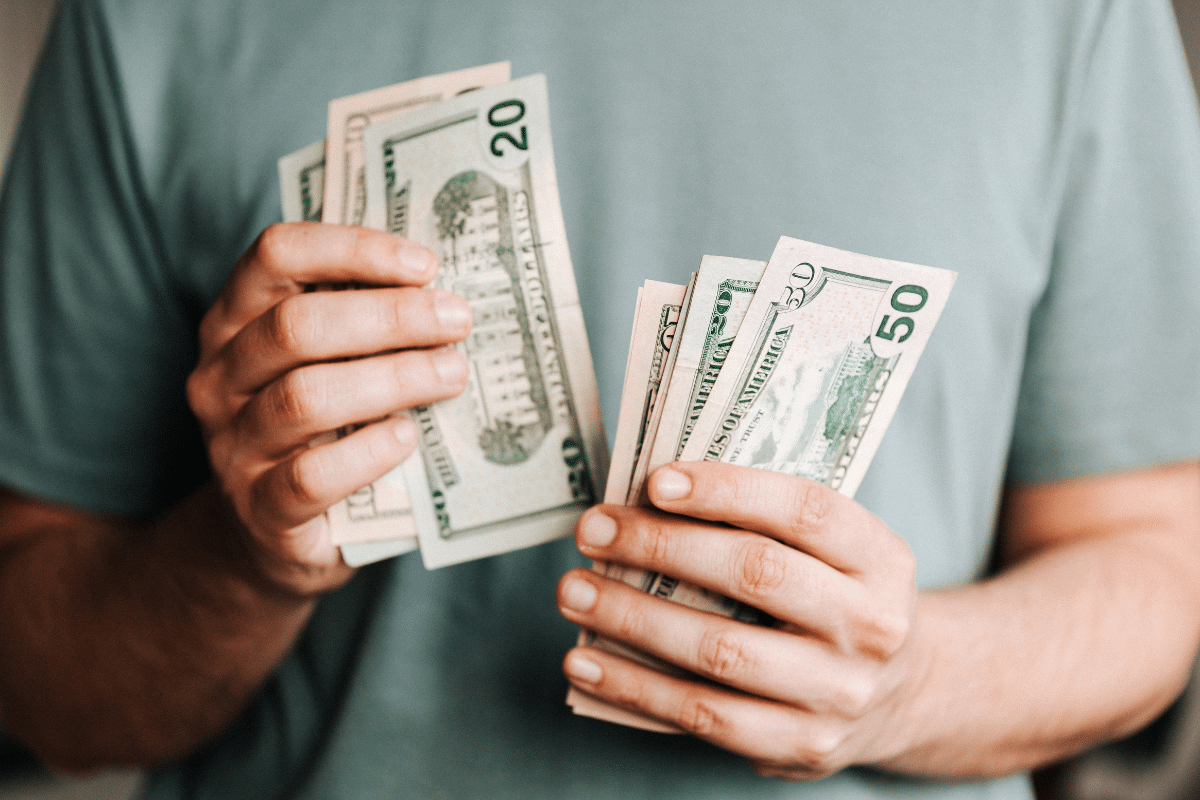 affluence more money isn't the answer man holding dollar bills