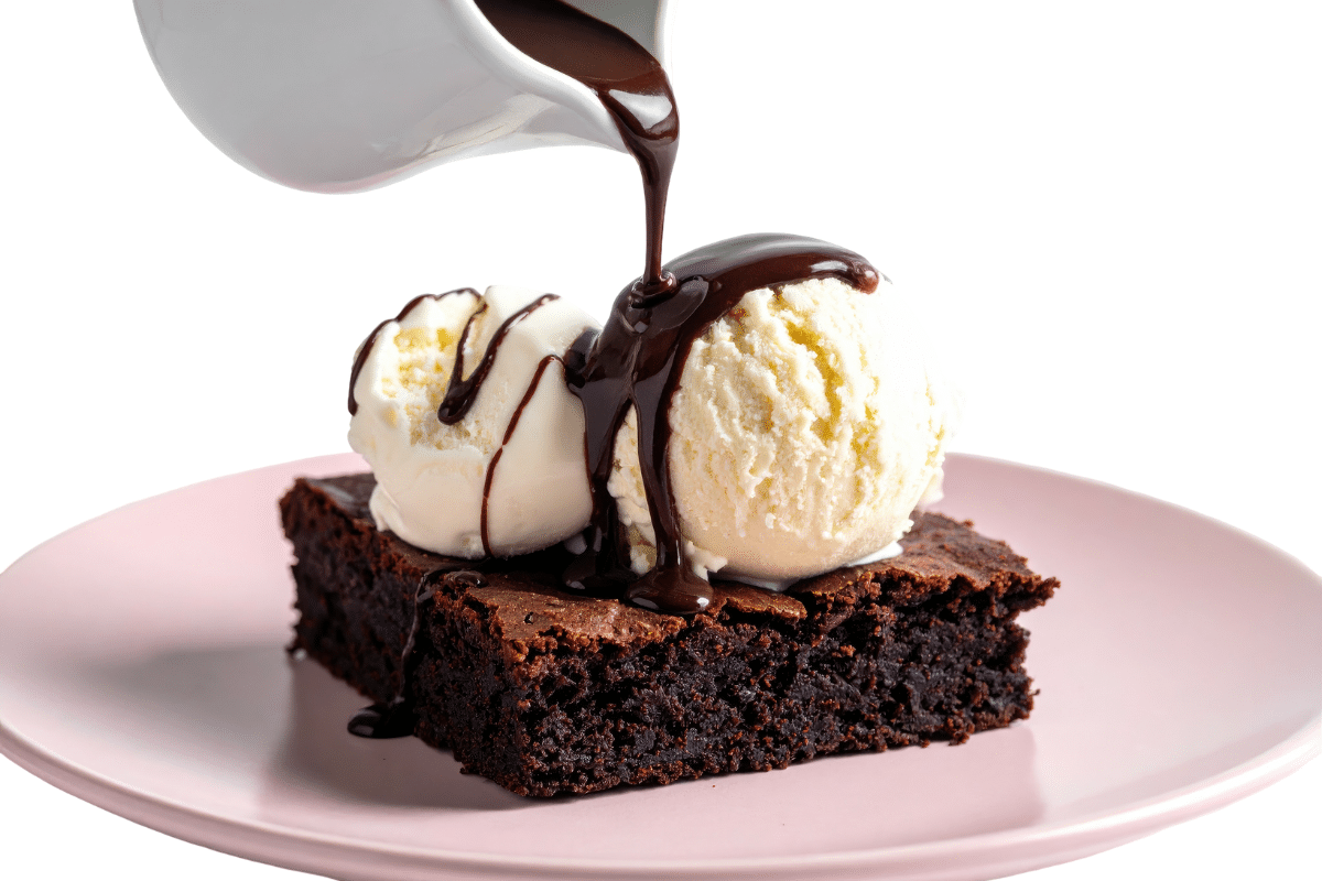 pouring hot fudge on brownie and ice cream