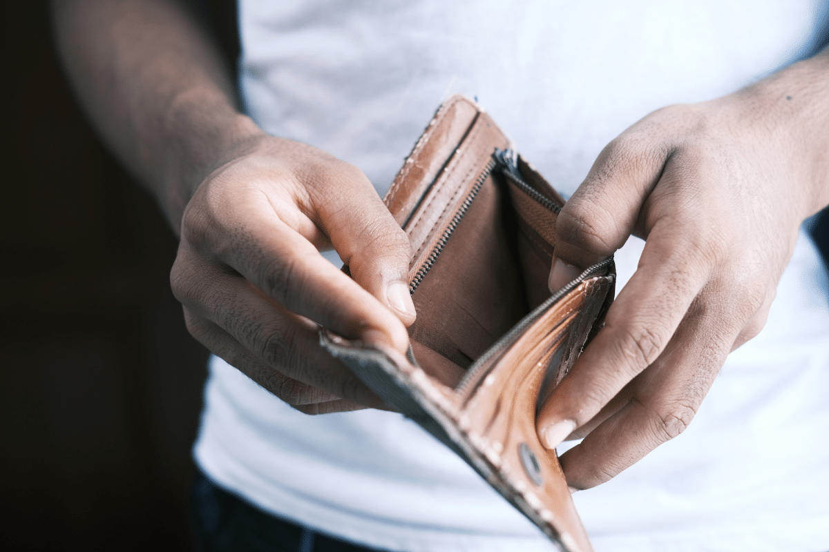 overspending habits man opening empty wallet