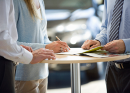 man and woman signing an extended warranty in a car dealership