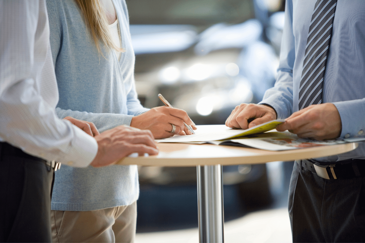 man and woman signing an extended warranty in a car dealership