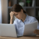 small money mistakes woman sitting at her laptop reviewing bills