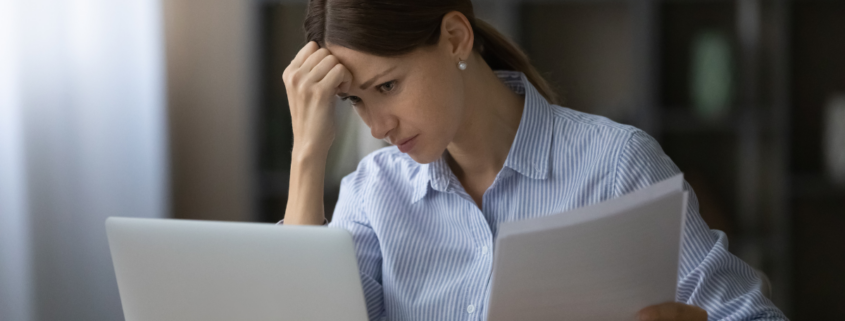 small money mistakes woman sitting at her laptop reviewing bills