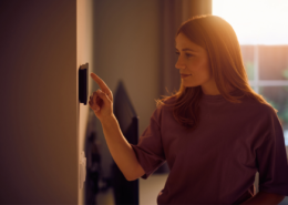 Woman Adjusting Smart Home Device on the Wall how to lower your electric bill