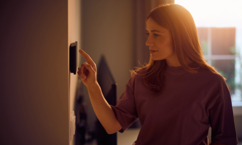 Woman Adjusting Smart Home Device on the Wall how to lower your electric bill