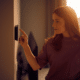 Woman Adjusting Smart Home Device on the Wall how to lower your electric bill