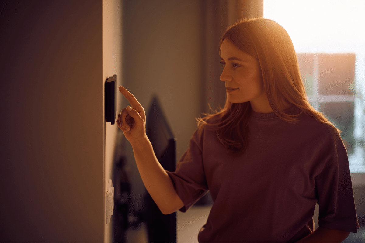 Woman adjusting a wall-mounted smart thermostat