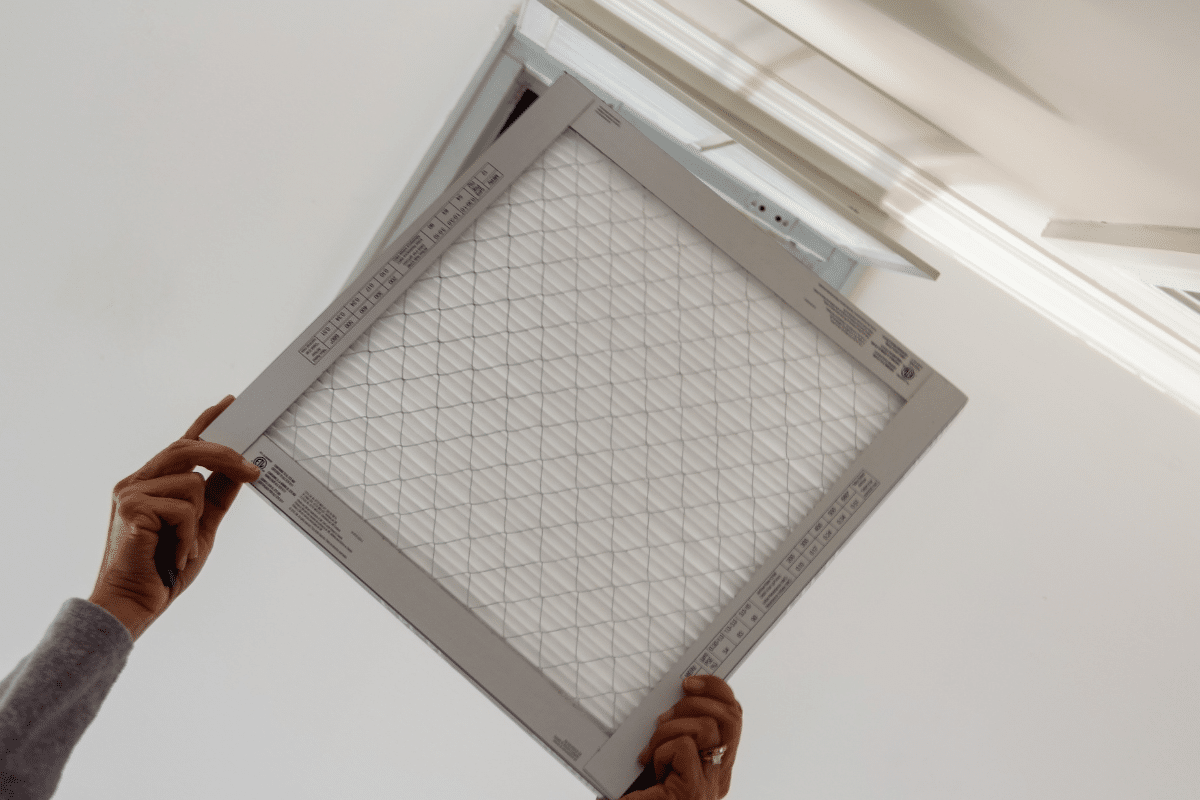 Woman installing an HVAC filter inside her home