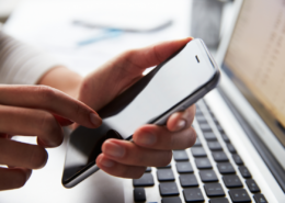 Woman using smartphone while checking monthly cellular data usage on laptop