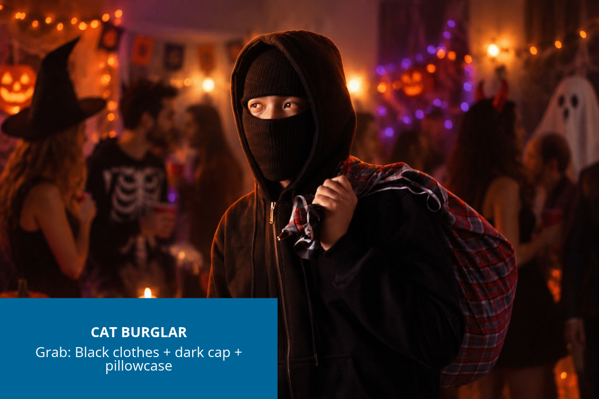 Person dressed as a cartoon cat burglar in black clothes and a dark cap, carrying a pillowcase
