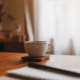 A cup of coffee, notebook, and pen on a table