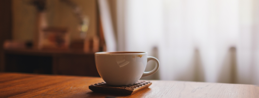 A cup of coffee, notebook, and pen on a table