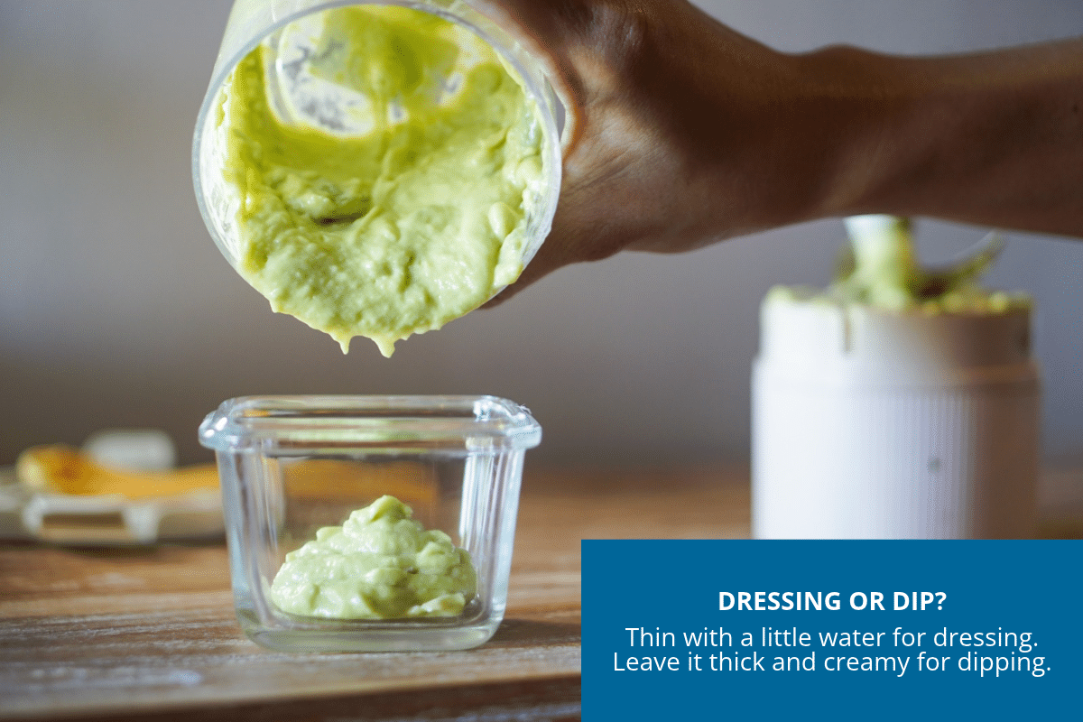 Emptying creamy avocado dip from blender into serving dish