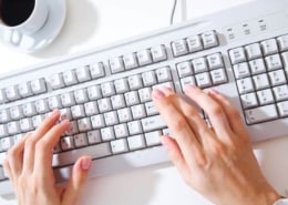 A person using a laptop computer sitting on top of a keyboard