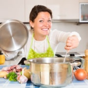 Young woman wearing an apron cooking a big pot of food