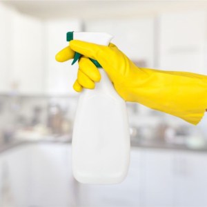 female hand in yellow rubber glove holding spray bottle of homemade cleaning solution
