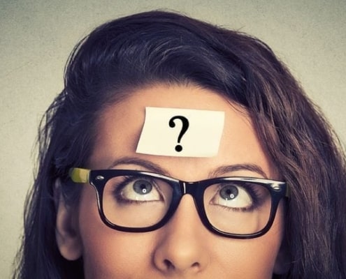 A close up of a woman in glasses looking at the camera, with Question mark