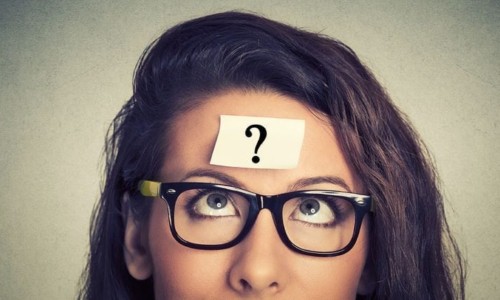 A close up of a woman in glasses looking at the camera, with Question mark