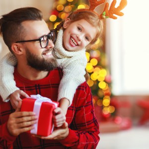 happy family father and child daughter giving christmas gift and embracing