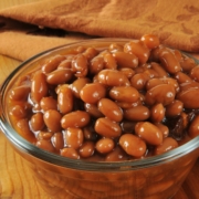 A cup of baked beans on a rustic wooden table
