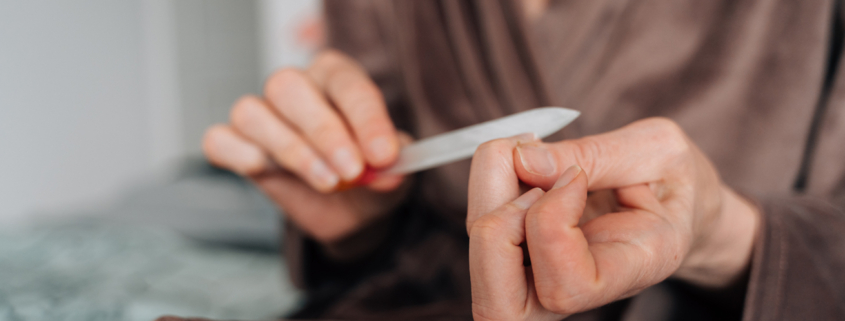 mature woman hands close-up using nail file for manicure at home.