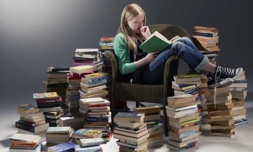A woman sitting next to a book shelf