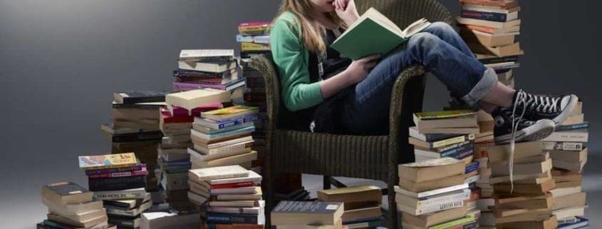 A woman sitting next to a book shelf