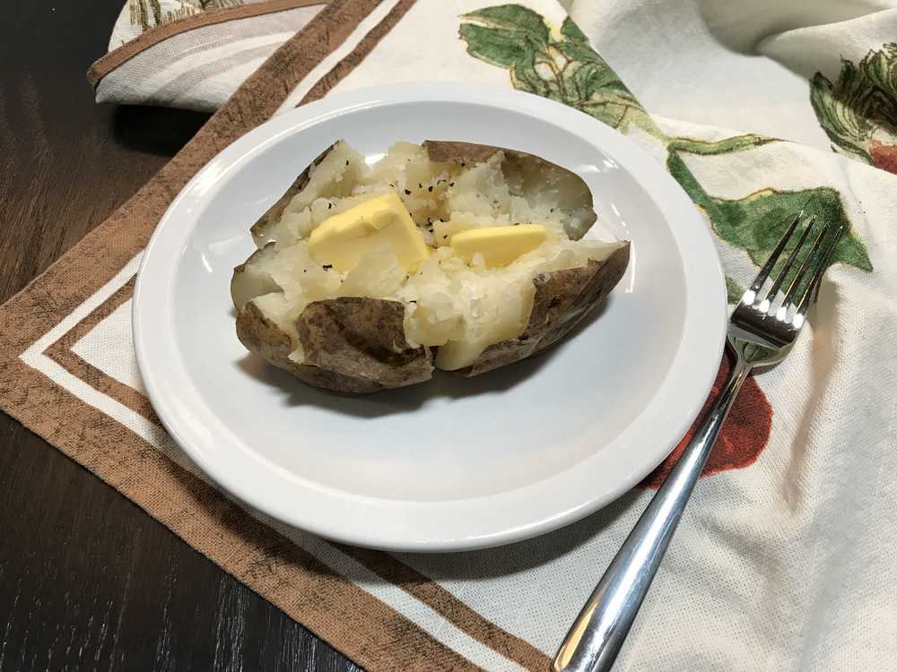 A plate of food on a table, with Baked potato