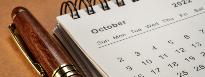 October 2022 - closeup of a small desktop calendar with a pen, time and business concept