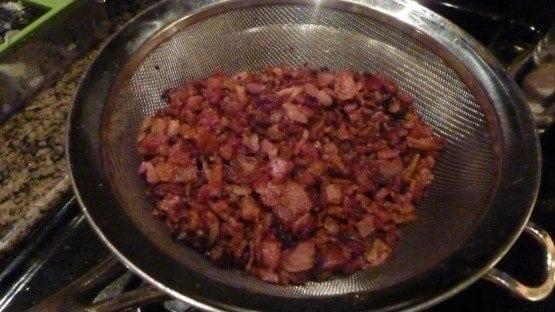 A bowl of food on a metal pan on a stove, with Bacon and Gift