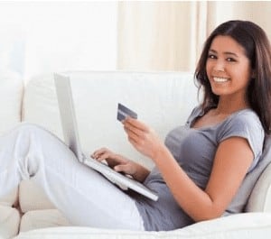 Young women shopping online with a credit card in her hand and a smile on her face
