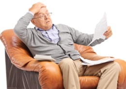Shocked senior gentleman looking at his bills in disbelief cut electricity bill