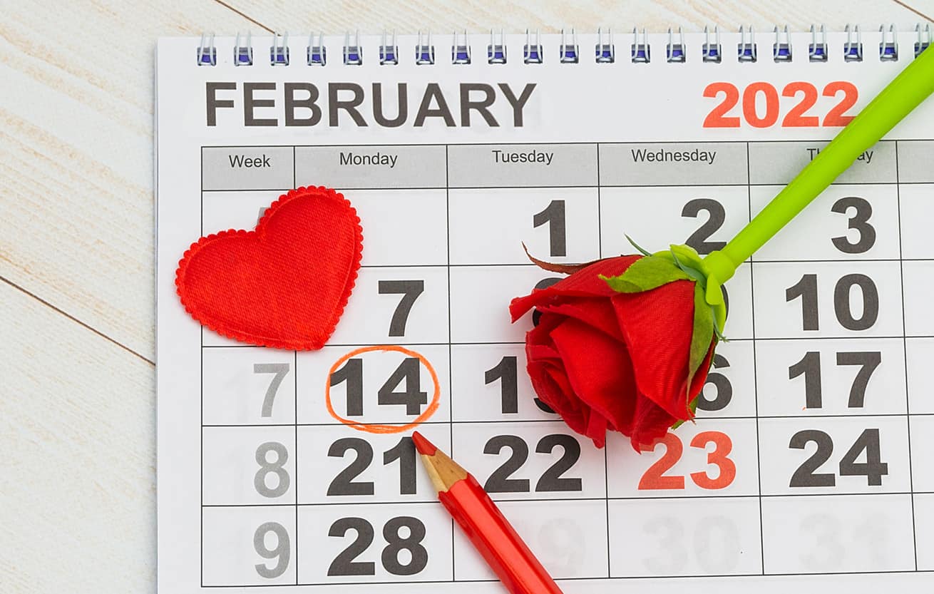 On the 2022 calendar, the date 14 February is marked in red pencil - Valentine's Day. Flat lay