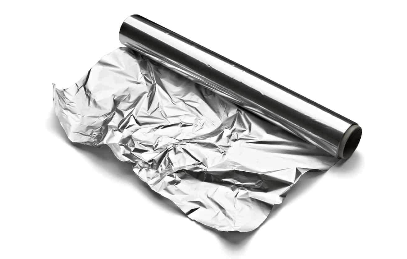 a roll of aluminum foil on white background slightly unrolled and crinkled