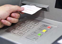 A hand taking a receipt of an Automated Teller Machine