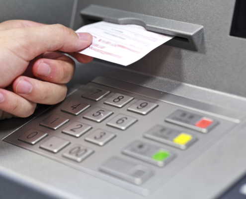 A hand taking a receipt of an Automated Teller Machine